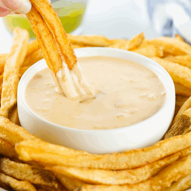 Air Fryer Animal Style Fries topped with melted cheese, caramelized onions, and creamy spread served on a tray.