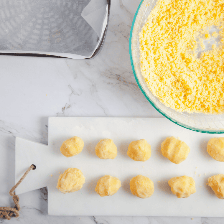 Cookie dough balls being shaped and flattened with fingers or spoon.