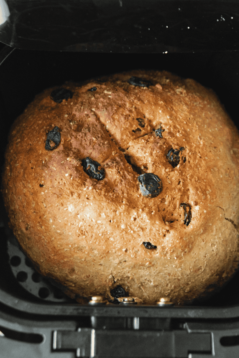 Scored Boston brown bread loaf on parchment paper in the air fryer basket, ready to cook