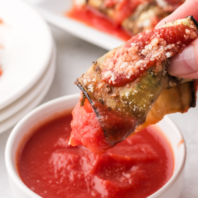 Golden-brown Air Fryer Eggplant Rollatini topped with melted cheese and marinara sauce, garnished with fresh basil.