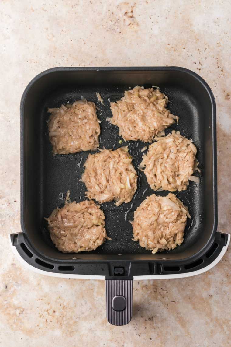 latkes placed in air fryer basket on parchment paper