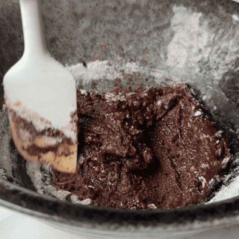 Adding chocolate chips and colorful M&M&rsquo;s to the cookie dough and mixing evenly.