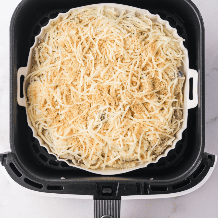 Mozzarella cheese melting over Air Fryer Turkey Tetrazzini inside air fryer basket.