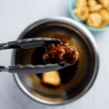 Plate of crispy Buffalo Wild Wings-style cauliflower wings coated in tangy buffalo sauce, garnished with parsley and served with dipping sauce.