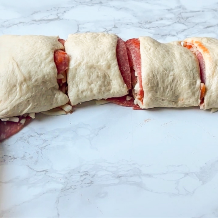 Pizza rolls being cut into slices before air frying.