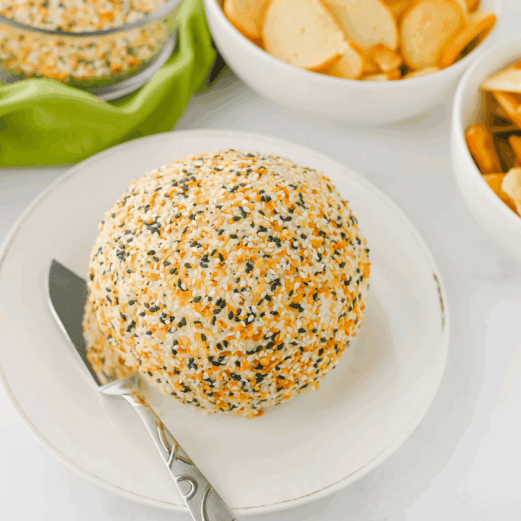 Everything Bagel Cheese Ball coated with everything bagel seasoning, served with crackers and fresh vegetables for dipping.