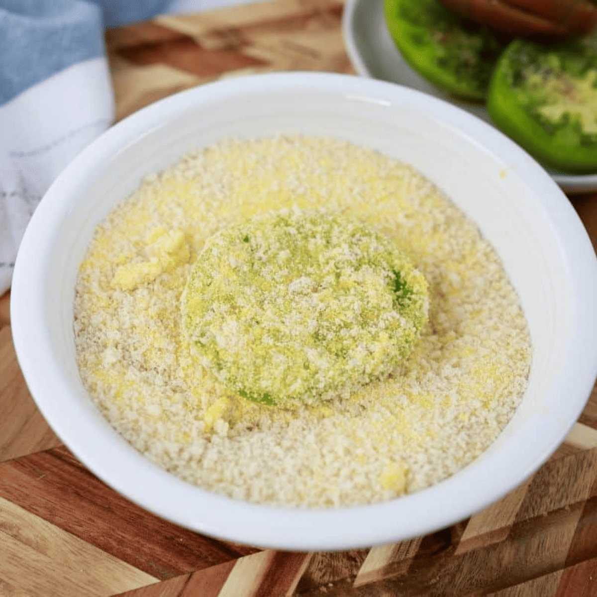 Dredging station with bowls of seasoned flour, beaten eggs, and seasoned breadcrumbs with cornmeal for coating green tomatoes.