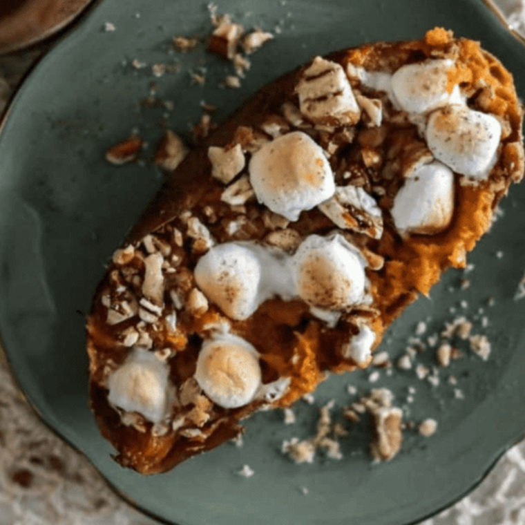 A perfectly baked sweet potato loaded with toasted marshmallows, creamy honey cinnamon butter, and a generous drizzle of rich caramel sauce, replicating the Texas Roadhouse favorite.