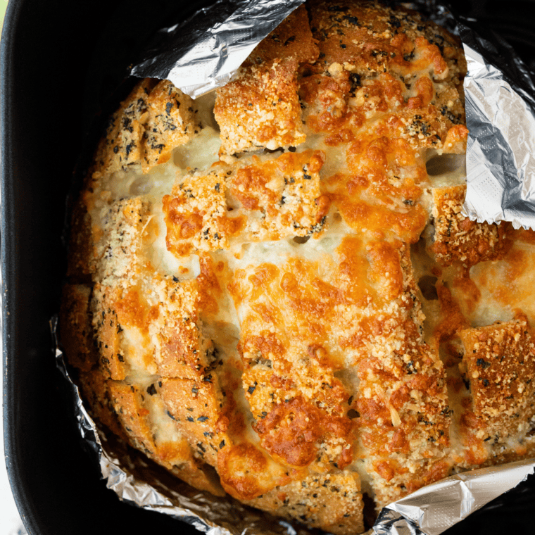 Golden, cheesy Air Fryer Mozzarella Pizza Bread topped with melted mozzarella and served with marinara sauce on a wooden board.