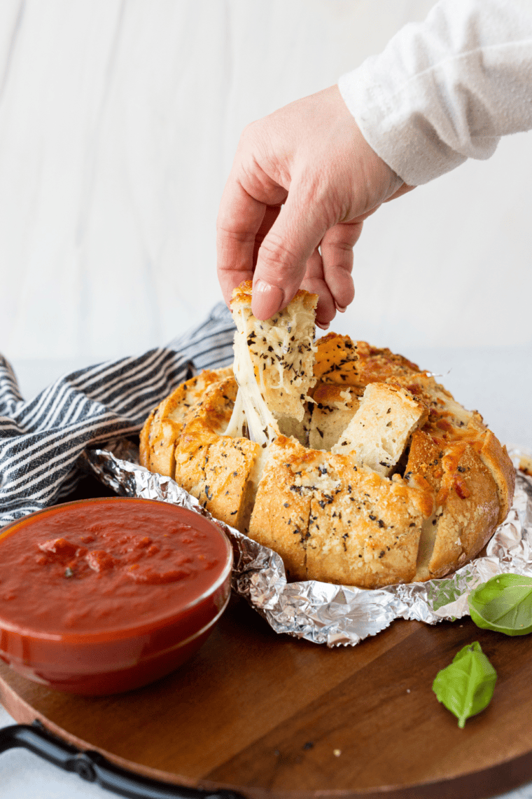 Air Fryer Mozzarella Pizza Bread with melted mozzarella cheese, golden crust, and marinara sauce on the side, served on a wooden board.