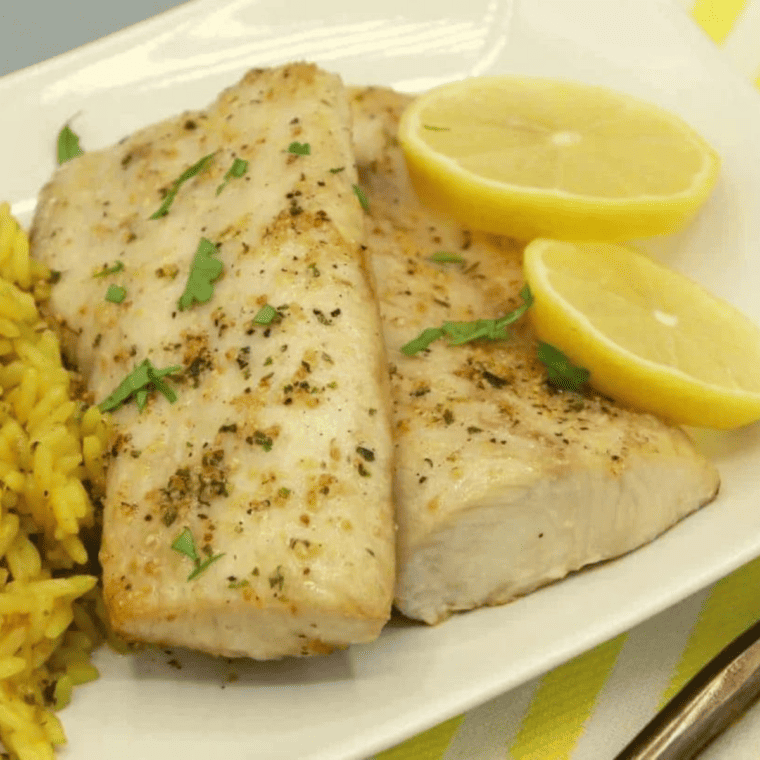 closeup: air fryer mahi mahi on a plate with rice and lemon wedges