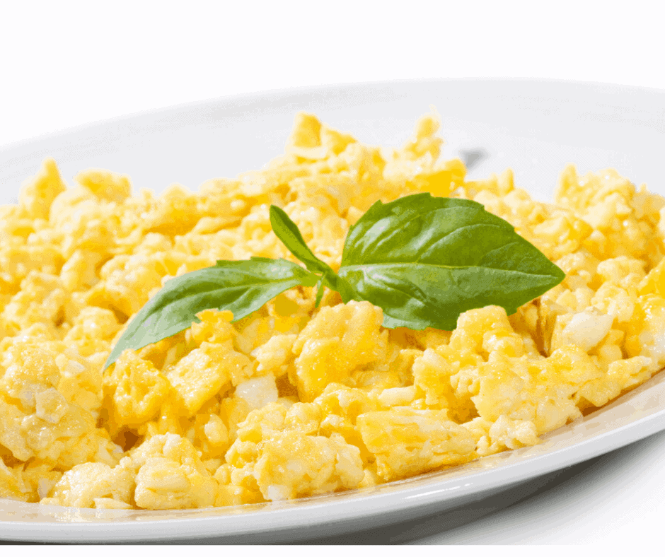 platter of scrambled eggs topped with basil leaves