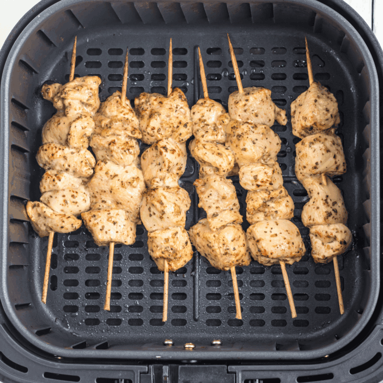 Cooked cilantro lime chicken skewers on a plate, garnished with chopped cilantro and lime wedges, ready to eat.