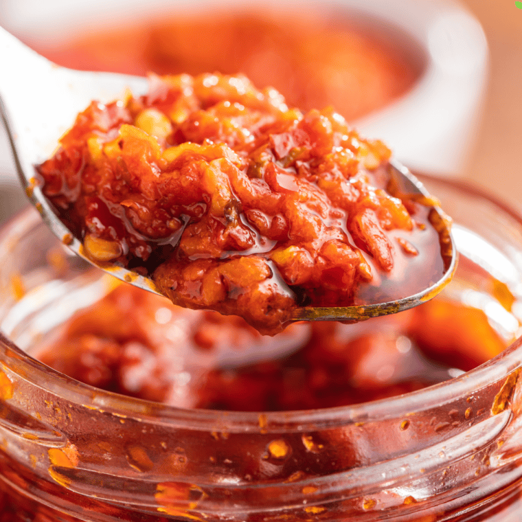 A jar of homemade chili garlic sauce with fresh red chilies and garlic, replicating the bold flavor of Huy Fong's signature sauce.