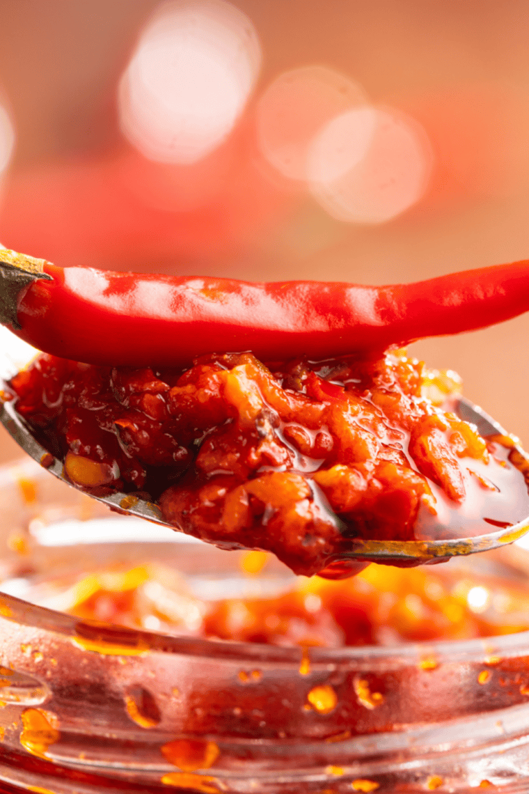 A jar of homemade chili garlic sauce with fresh red chilies and garlic, replicating the bold, spicy flavor of Huy Fong's signature chili garlic sauce.