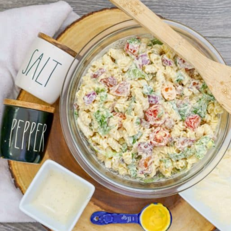 A close-up shot of a spoon serving creamy Instant Pot BLT Pasta Salad, showing the crispy bacon and fresh veggies.