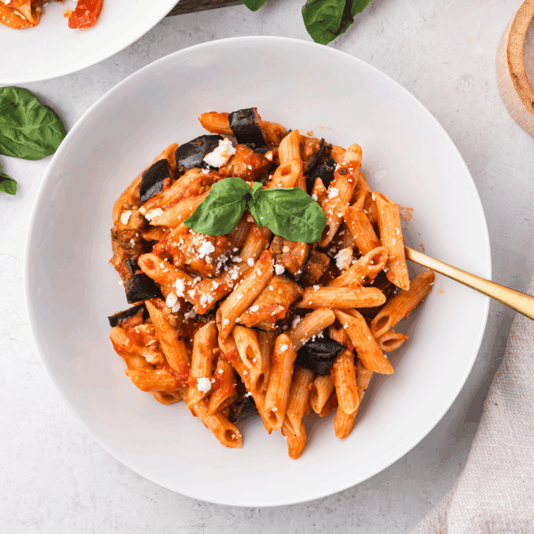 Homemade Olive Garden-style marinara sauce in a bowl with fresh herbs and a spoon