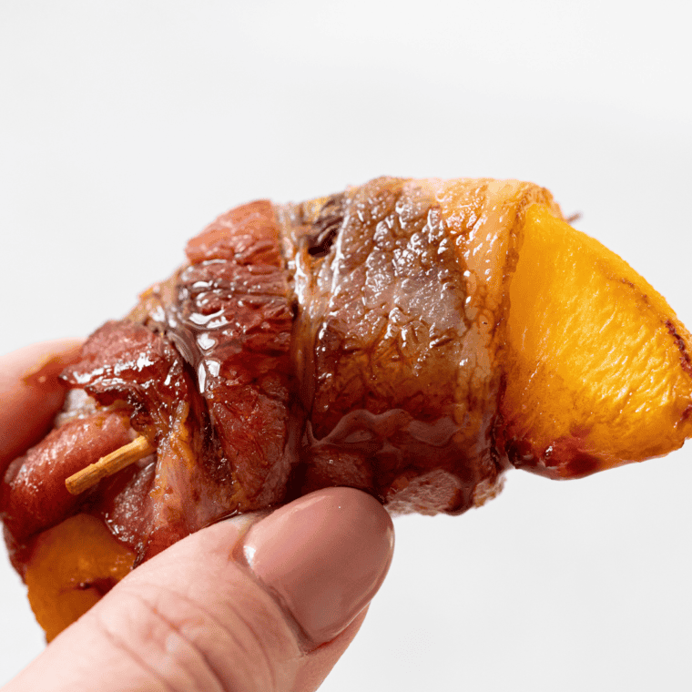 Air Fryer Bacon Wrapped Peaches with crispy bacon and juicy peach slices, served as a savory-sweet appetizer.