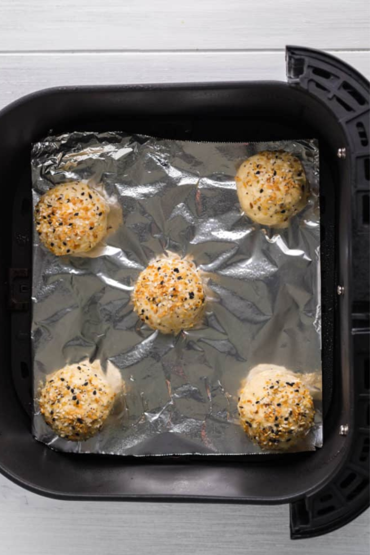 Batch of Dunkin donut minis in an air fryer basket, the air fryer basket is lined with foil, but you can use parchment paper.