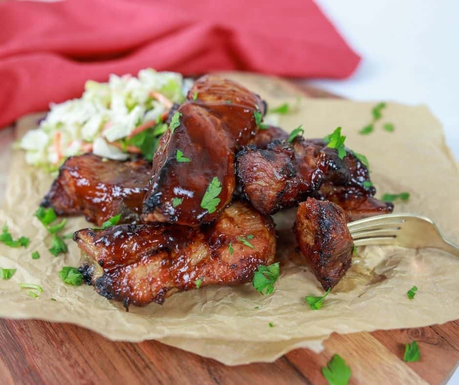 Cooked country-style ribs on top of parchment paper with coleslaw