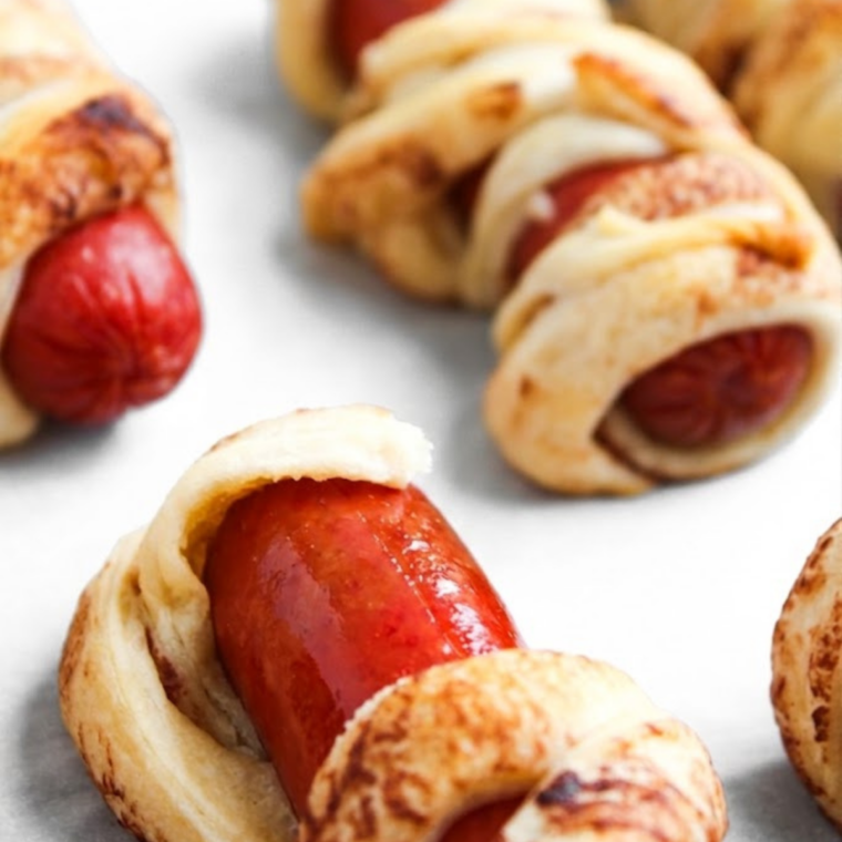 Air fryer crescent roll hot dogs wrapped in flaky dough with melted cheese, cooked until golden brown, crispy, and cheesy inside.