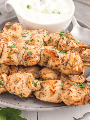 Air Fryer Greek Chicken Kebabs on a white plate with a side of creamy tzatziki sauce