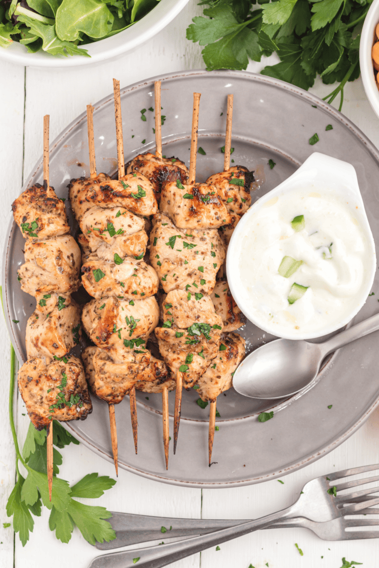 Air fryer Greek chicken kebabs with herbs, lemon, and vegetables on skewers.
