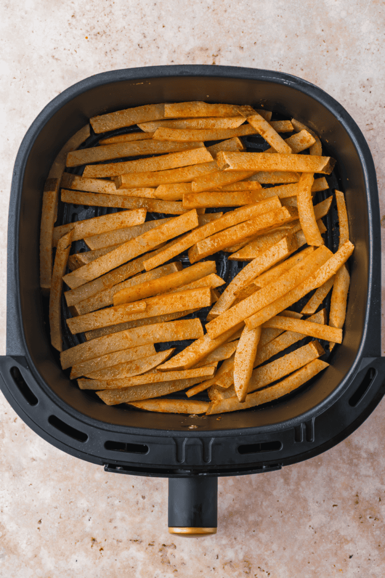 Preheating the air fryer to 400°F and cooking seasoned jicama fries for 15-20 minutes, flipping halfway, until golden and crispy.