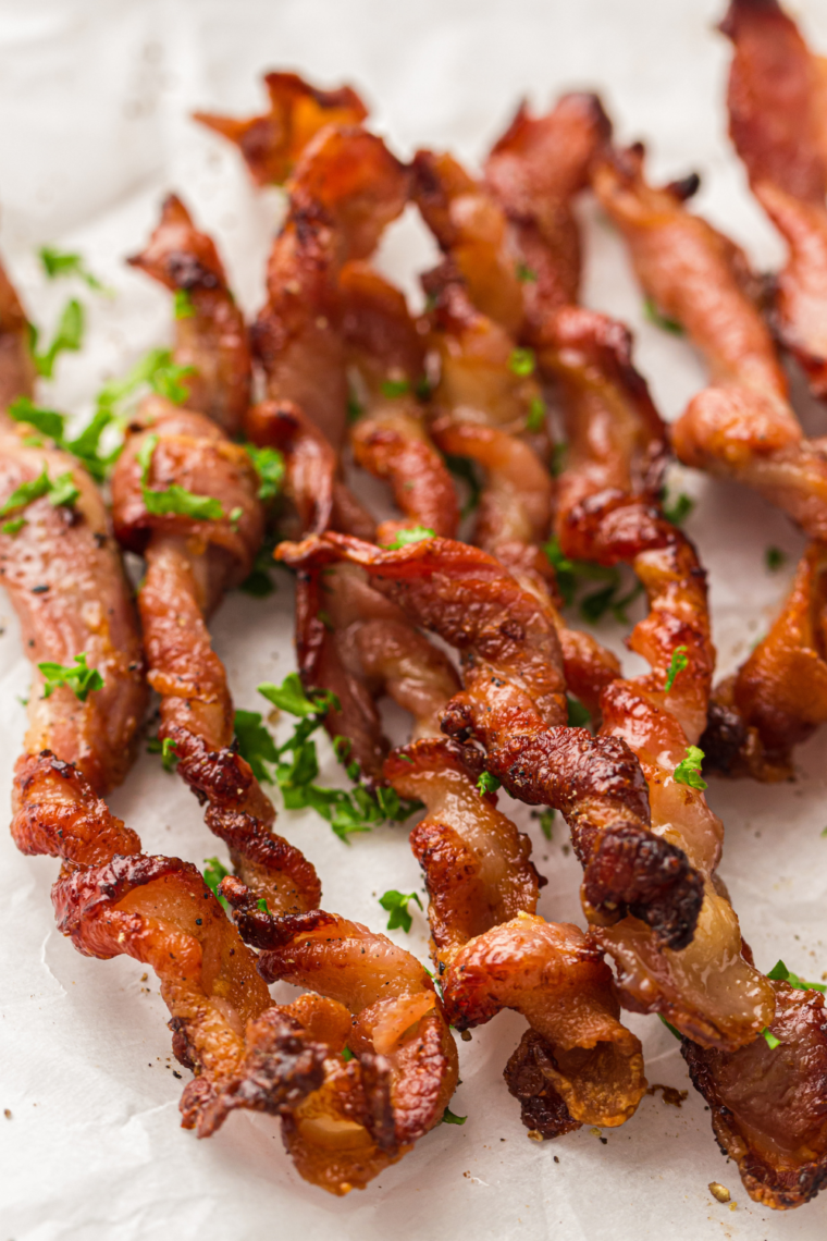 Plate of crispy, twisted bacon strips fresh from the air fryer, perfectly golden brown and ready to serve.