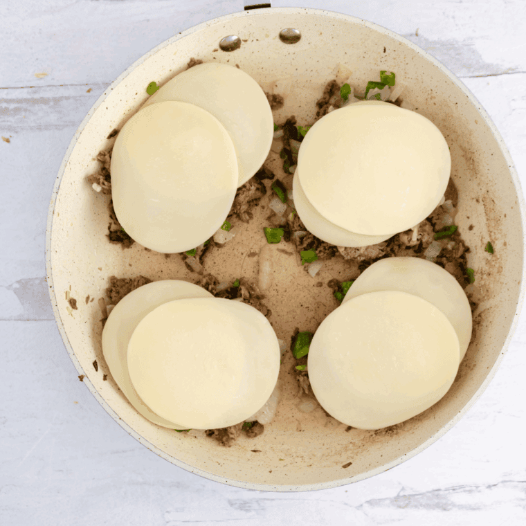  Dividing meat mixture and melting provolone cheese in skillet with lid.
