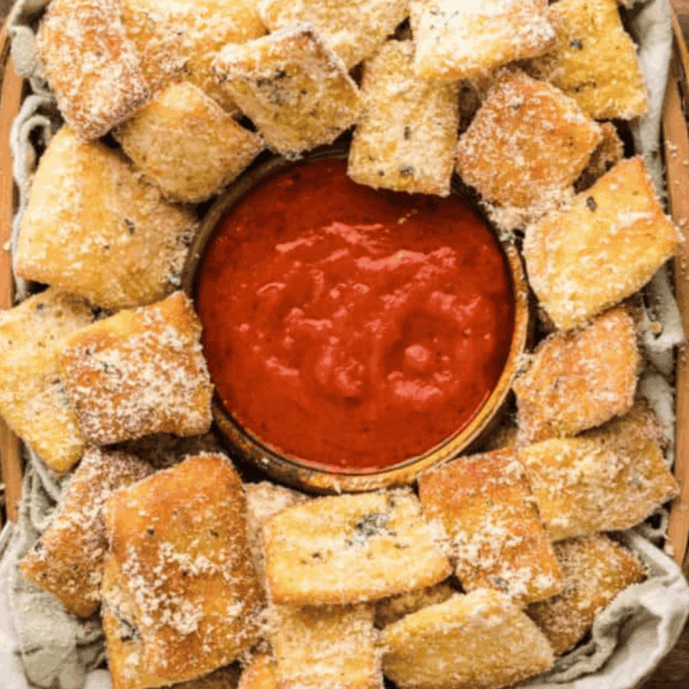 Bowl of homemade Domino&rsquo;s-style pizza sauce with a spoon and fresh herbs