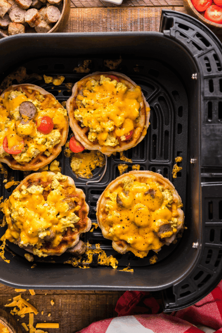Air Fryer Breakfast Pizza Waffle topped with scrambled eggs, sausage, cherry tomatoes, and melted cheddar cheese, served hot and ready to eat.