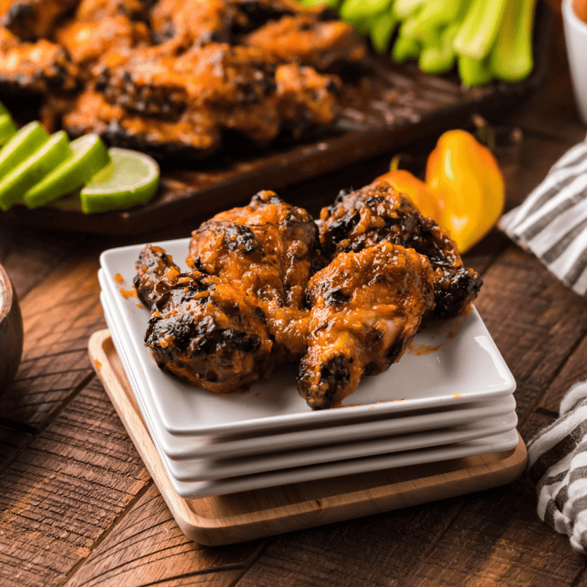 Crispy Wingstop-style mango habanero wings coated in spicy, sweet sauce on a white plate with celery sticks and dipping sauce.