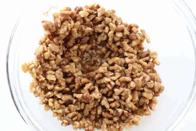 overhead process shot: walnuts tossed in butter, cinnamon, and sugar in a large glass bowl