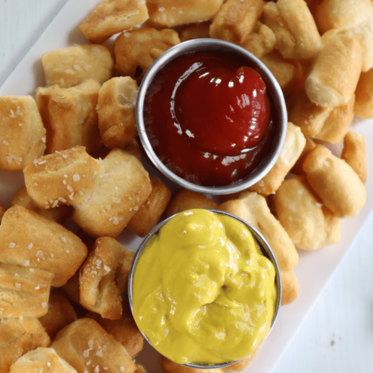 Golden air fryer bite-size pretzels piled in a bowl with coarse salt