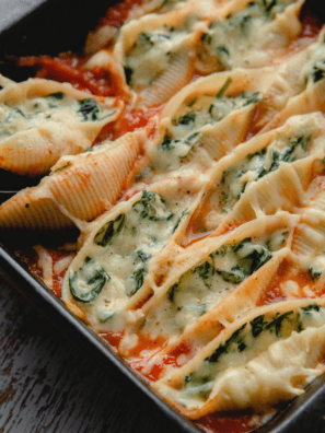 Air fryer stuffed spinach pasta shells on a white plate, filled with ricotta and spinach and topped with melted mozzarella and marinara