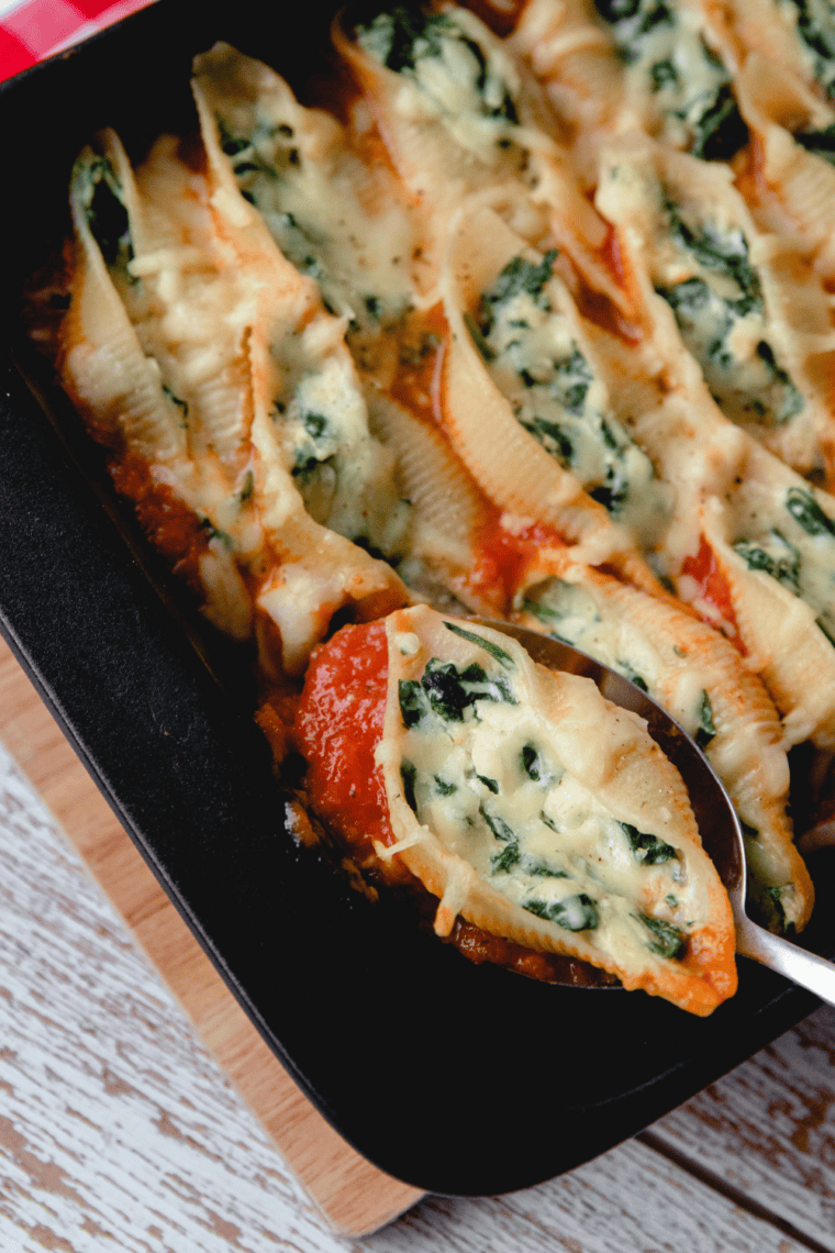 A plate of air fryer stuffed spinach pasta shells topped with melted mozzarella and marinara sauce