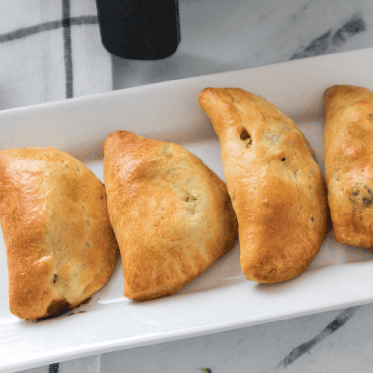 Flaky, golden brown air fryer turkey turnovers filled with savory turkey and cheese, served on a white plate