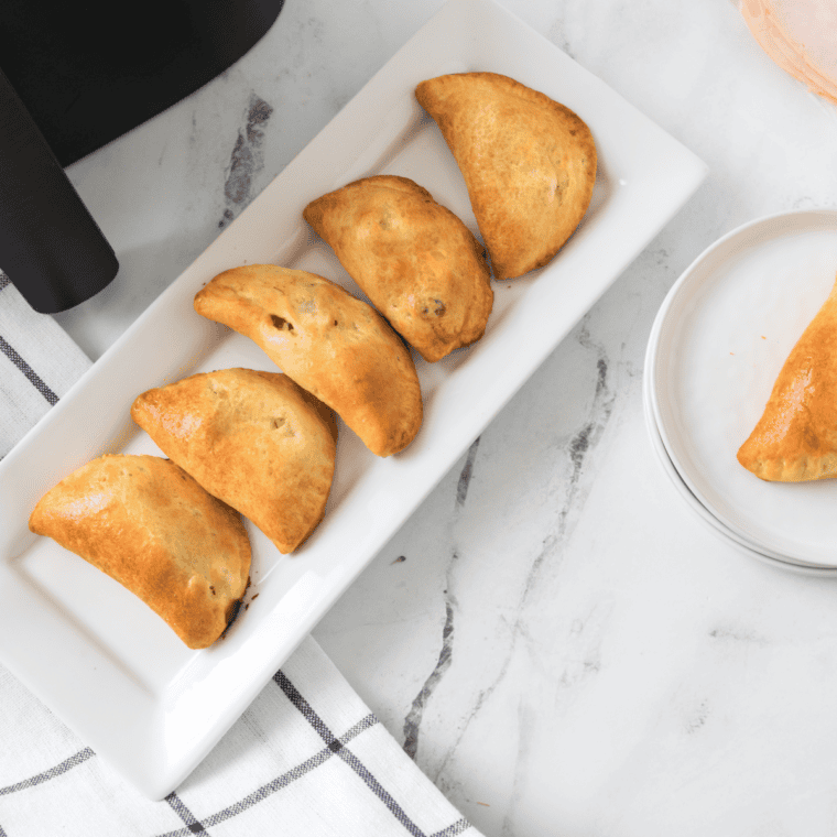 Flaky golden air fryer turkey turnovers filled with turkey and broccoli, stacked on a white plate ready to serve