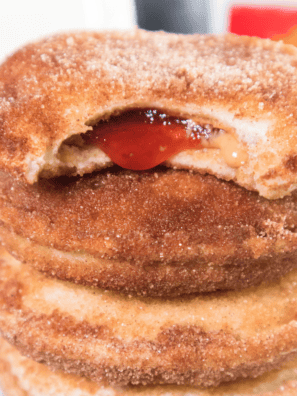 Air fryer Uncrustable donuts coated in cinnamon sugar, stacked on a plate and ready to serve