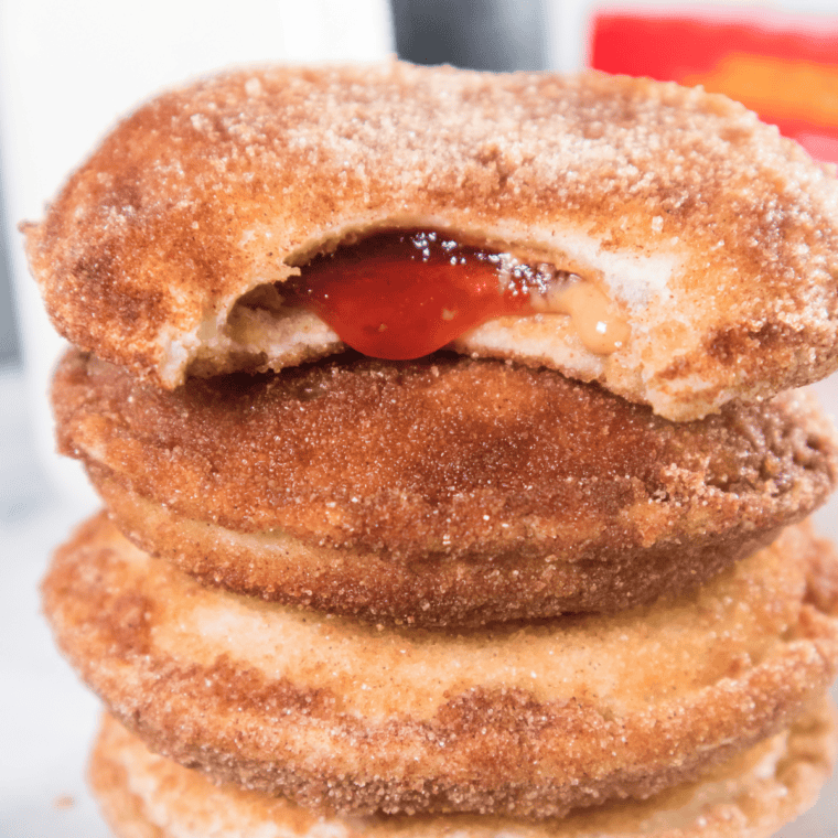 Air fryer Uncrustable donuts coated in cinnamon sugar, stacked on a plate and ready to serve