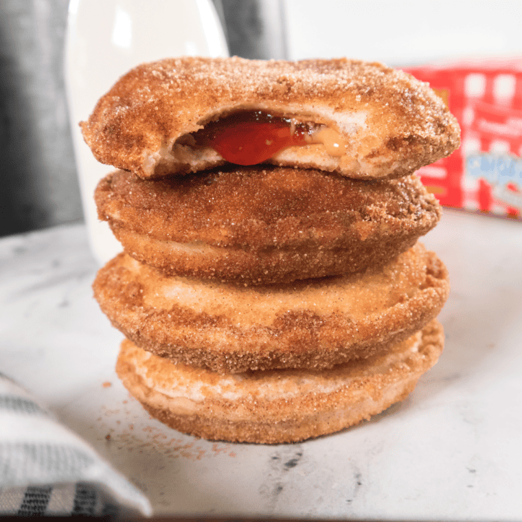 Air fryer Uncrustable donuts coated in cinnamon sugar, stacked on a plate ready to enjoy!