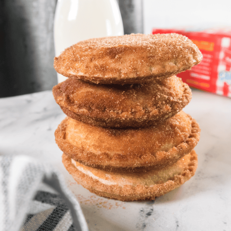 Air fryer Uncrustable donuts coated in cinnamon sugar, stacked on a white plate ready to eat