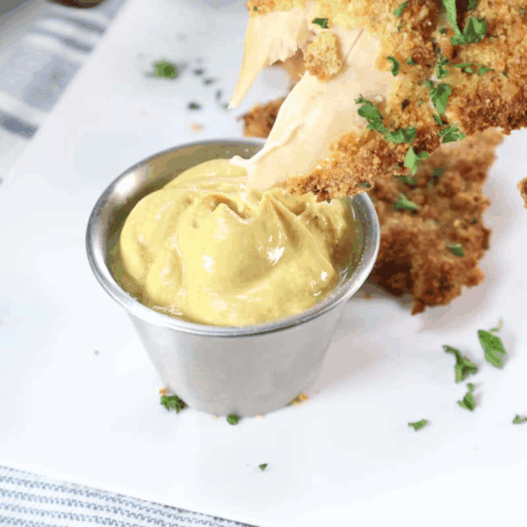Small bowl of homemade McDonald’s hot mustard copycat sauce with chicken nuggets.