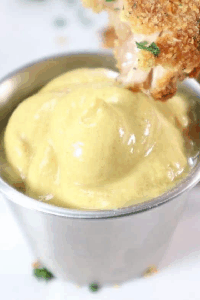 Small bowl of homemade copycat McDonald’s hot mustard sauce with chicken nuggets on the side.