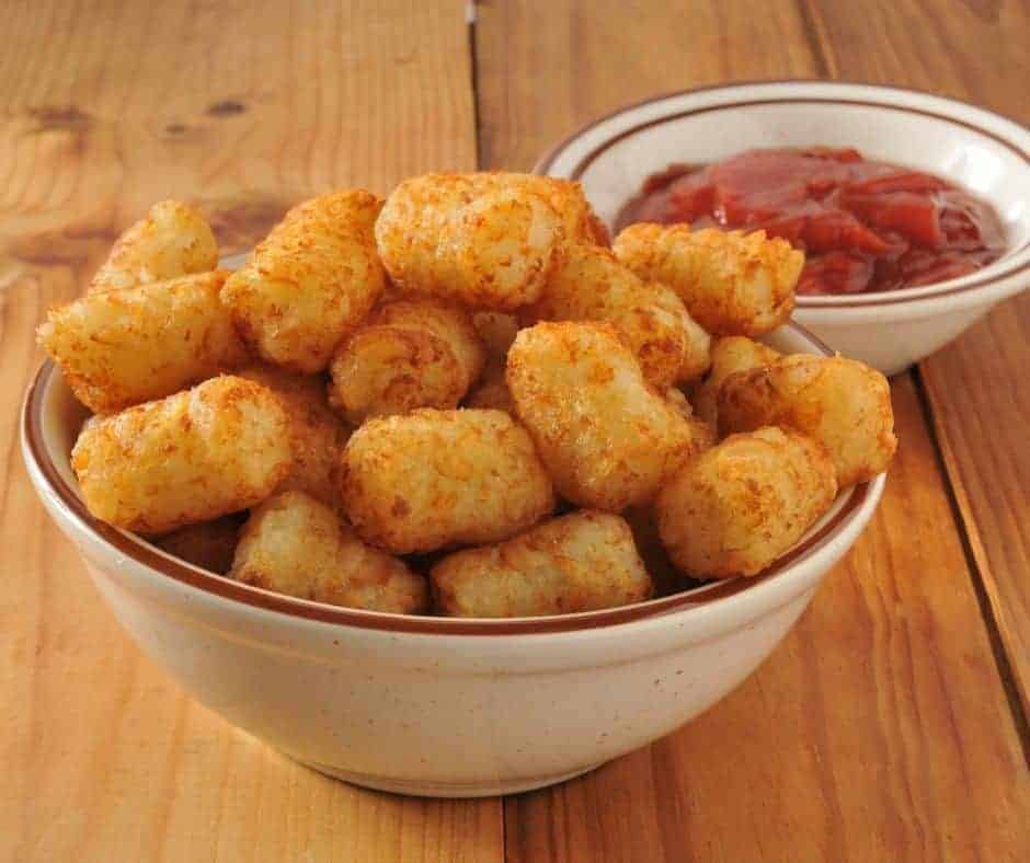 air fryer tater tots piled in a bowl with a separate bowl of ketchup