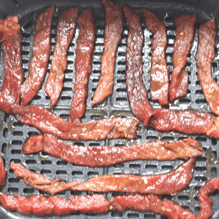 overhead closeup: air fryer beef jerky cooking in the air fryer basket 