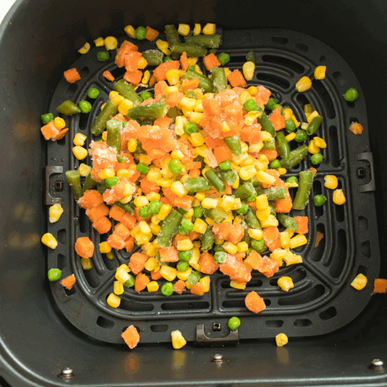 Spreading frozen vegetables in the air fryer basket, seasoning, and cooking at 350°F.