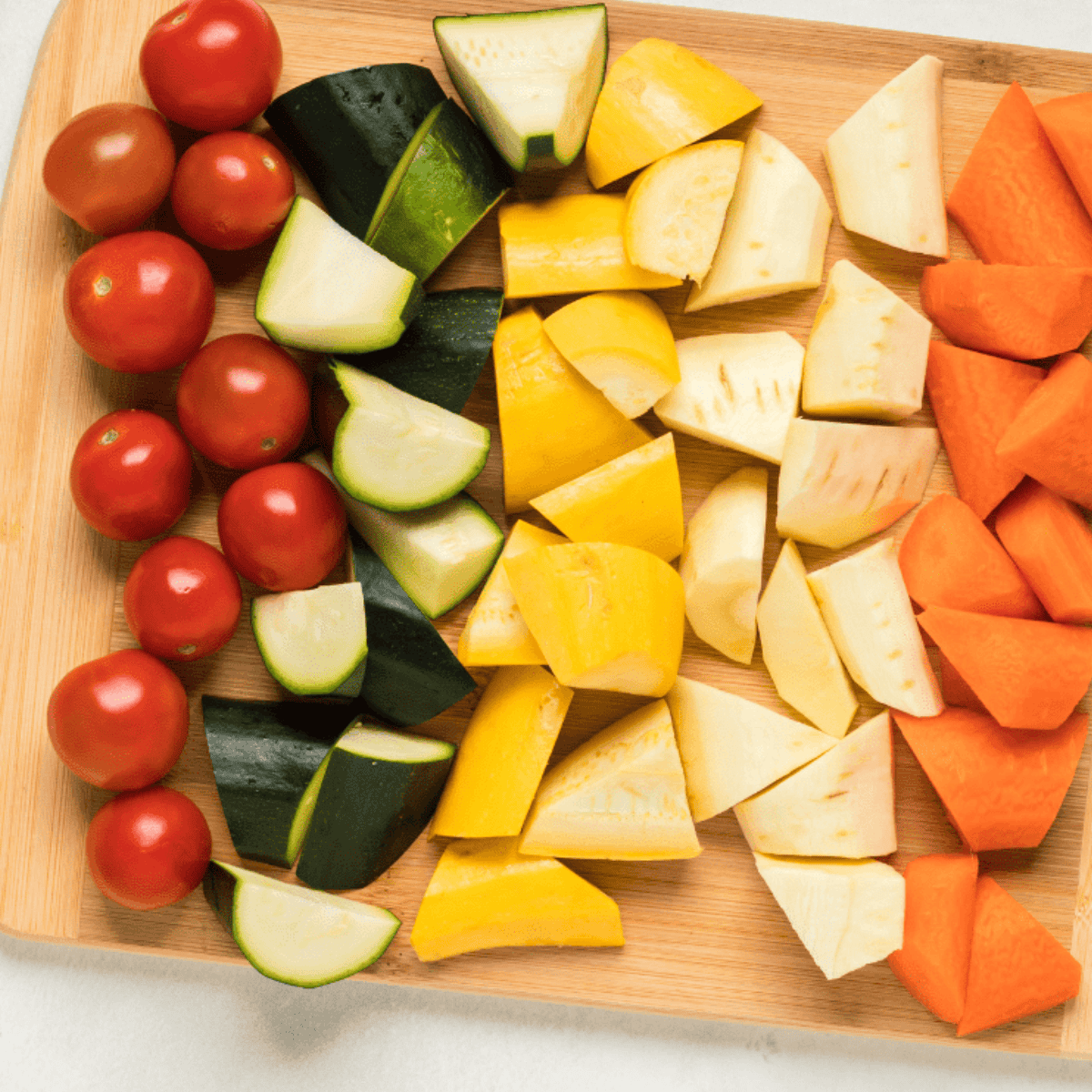 Chopped carrots, parsnips, zucchini, and yellow squash on a cutting board, ready for air frying.