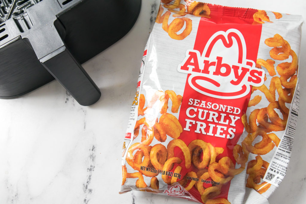 bag of frozen Arby's seasoned curly fries next to an air fryer